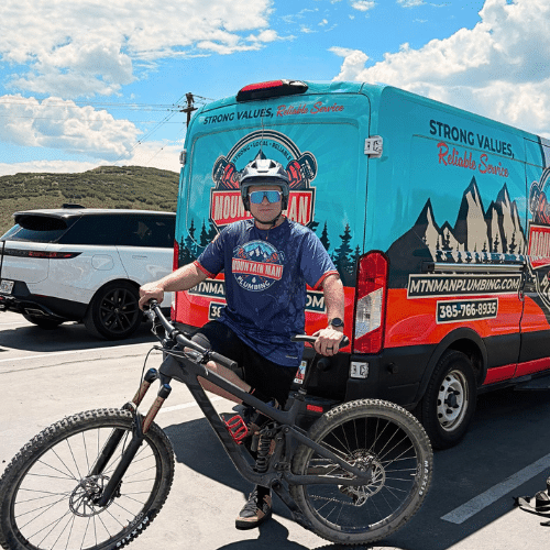 Tyler Nerdin with a mountain bike beside the Mountain Man Plumbing van